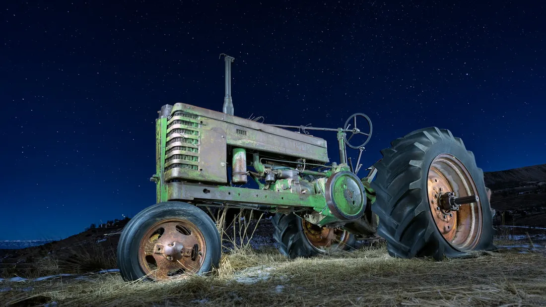 Alter grüner Traktor bei Nacht unter Sternenhimmel